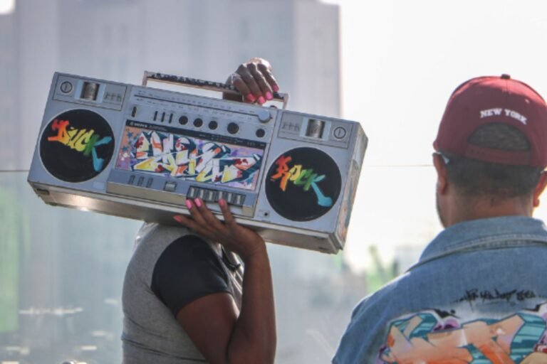 Uma capa de ilustra a mostra HIP-HOP 80’sp.Um rapaz segura uma caixa de som nos ombros